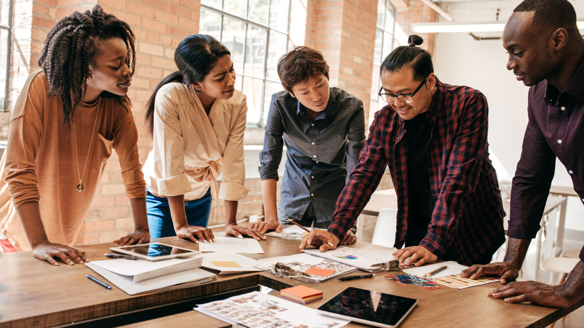 A diverse group of people collaborating on a project at a table, sharing ideas and working together.